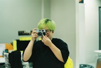a man with green hair taking a picture with a camera